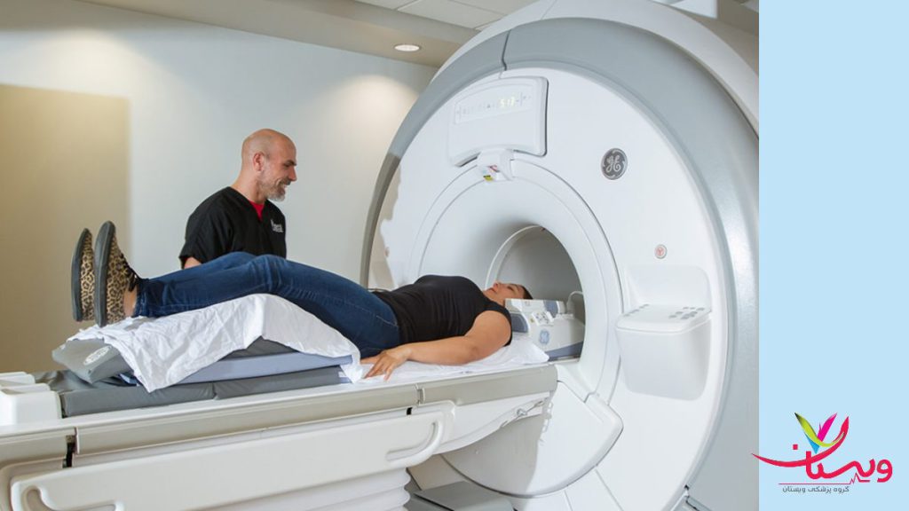 اماده شدن برای انجام اسکن ام ار ای بیماری که برای تشخیص اختلالتش به کمک پرستار وارد دستگاه ام ار ای میشود